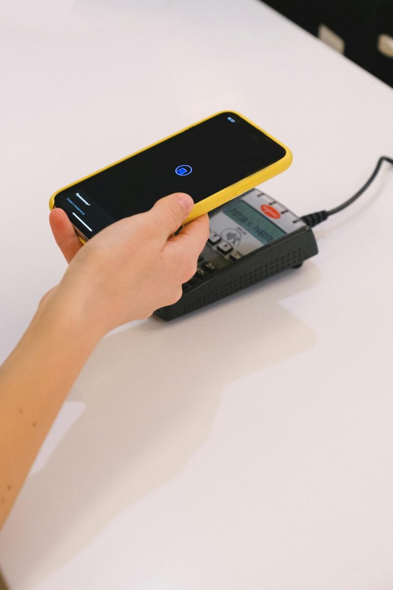 Person using a smartphone for contactless payment on a terminal. Simplifies transactions.
